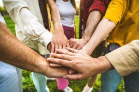Group,Of,People,Stacking,Hands,Together,-,Team,Building,Celebrating